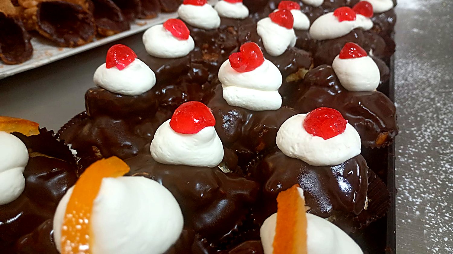 Bignè glassati al cioccolato con panna e ciliegia